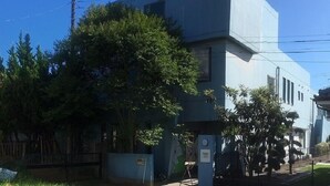 Un bâtiment moderne doté d’un toit plat et d’un grand arbre à l’avant.