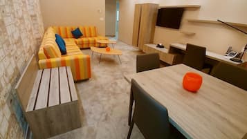 Un espacio moderno con un conjunto de sofás, una mesa de comedor y un televisor montado en la pared.