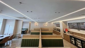 A modern restaurant interior with green cushioned booths, a counter with a menu, and a clean, minimalist design. - Greentree Inn Huaian Xuyi Royal Garden Express Hotel (Huai'an)