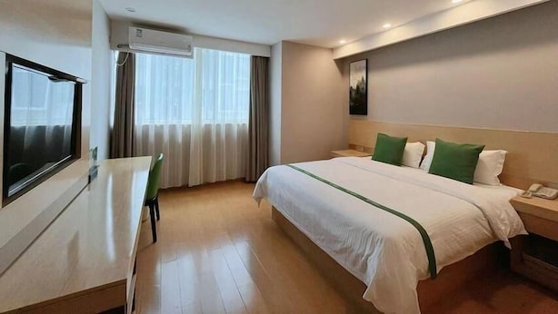 A hotel room with a bed, a desk, a chair, a TV, and an air conditioning unit. - Greentree Inn Huaian Xuyi Royal Garden Express Hotel (Huai'an)
