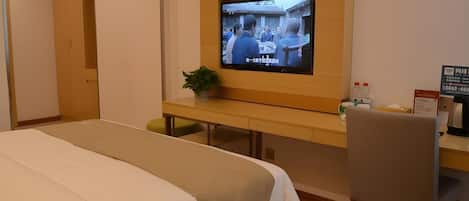 A hotel room with a bed, a desk, a television, and a chair.