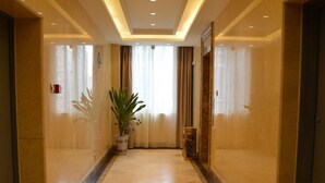 A polished hallway with a marble floor, a potted plant, and a large mirror on the wall. - Greentree Inn Huaian Xuyi Royal Garden Express Hotel (Huai'an)