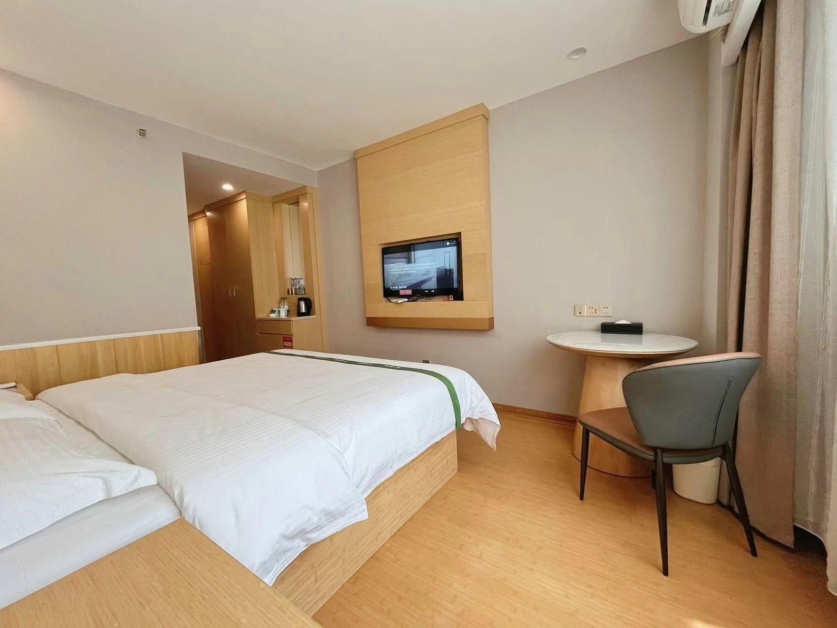 Une chambre d’hôtel avec un grand lit, un petit bureau, une chaise et un téléviseur fixé au mur.