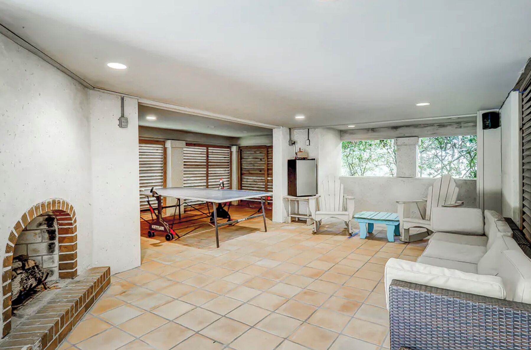 A spacious living area with a ping pong table, a fireplace, and a comfortable seating area with a sofa and chairs.