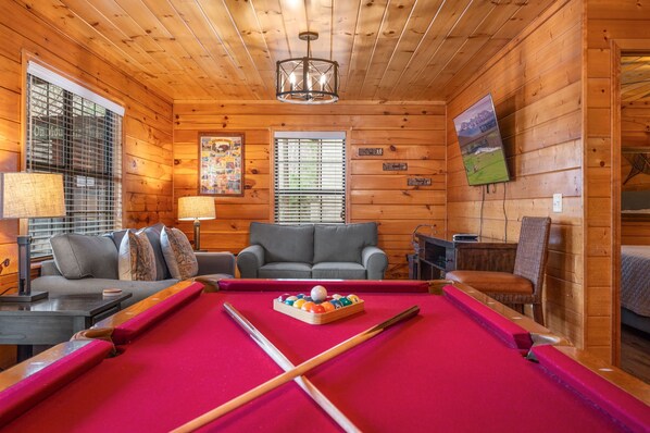 Une pièce confortable avec une table de billard, un canapé et un fauteuil.