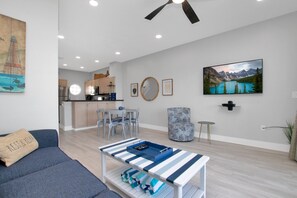 A modern living room with a sofa, a coffee table, and a dining area with chairs and a table.