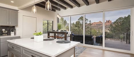 A modern kitchen with a large island, built-in appliances, and a view of a deck and mountains.