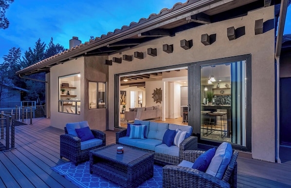 Une maison moderne dotée d’un patio aménagé avec des meubles en osier et une table à manger.