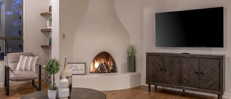 Una sala de estar moderna con chimenea, televisor y un espacio de descanso cómodo.