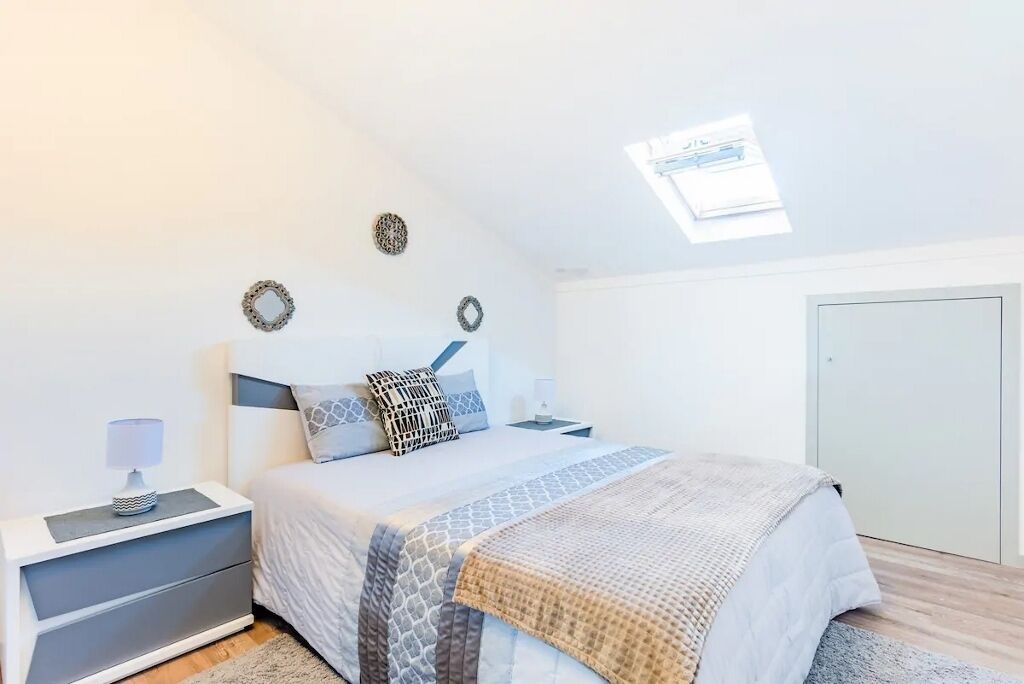 A bedroom with a bed, nightstands, a desk, and a wardrobe.