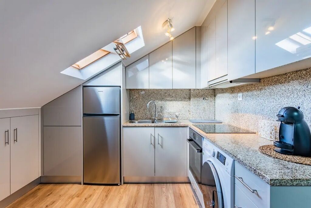 Eine moderne Küche mit eingebautem Geschirrspüler, einem Edelstahl-Kühlschrank und einer Arbeitsplatte aus Granit.