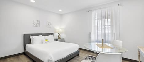 Une chambre d’hôtel comprenant un lit, une table de chevet, une lampe et une table ronde en verre avec des chaises.