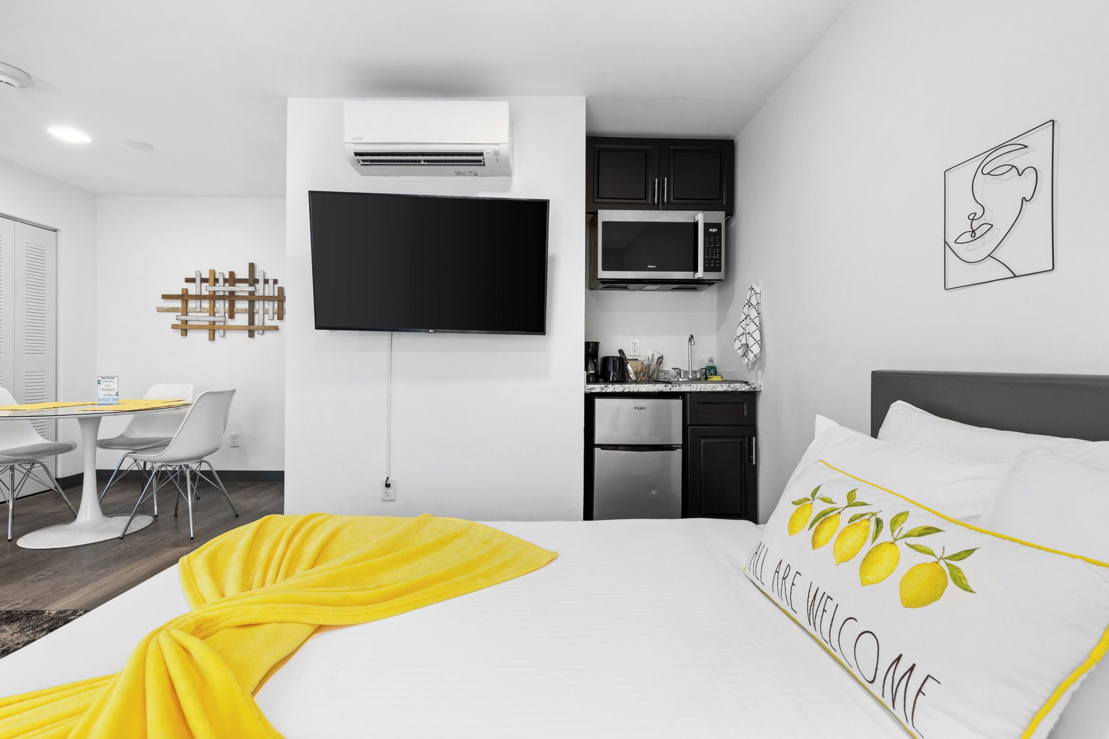 Una habitación de hotel moderna con una cama, un televisor de pantalla plana, una kitchenette y un comedor.