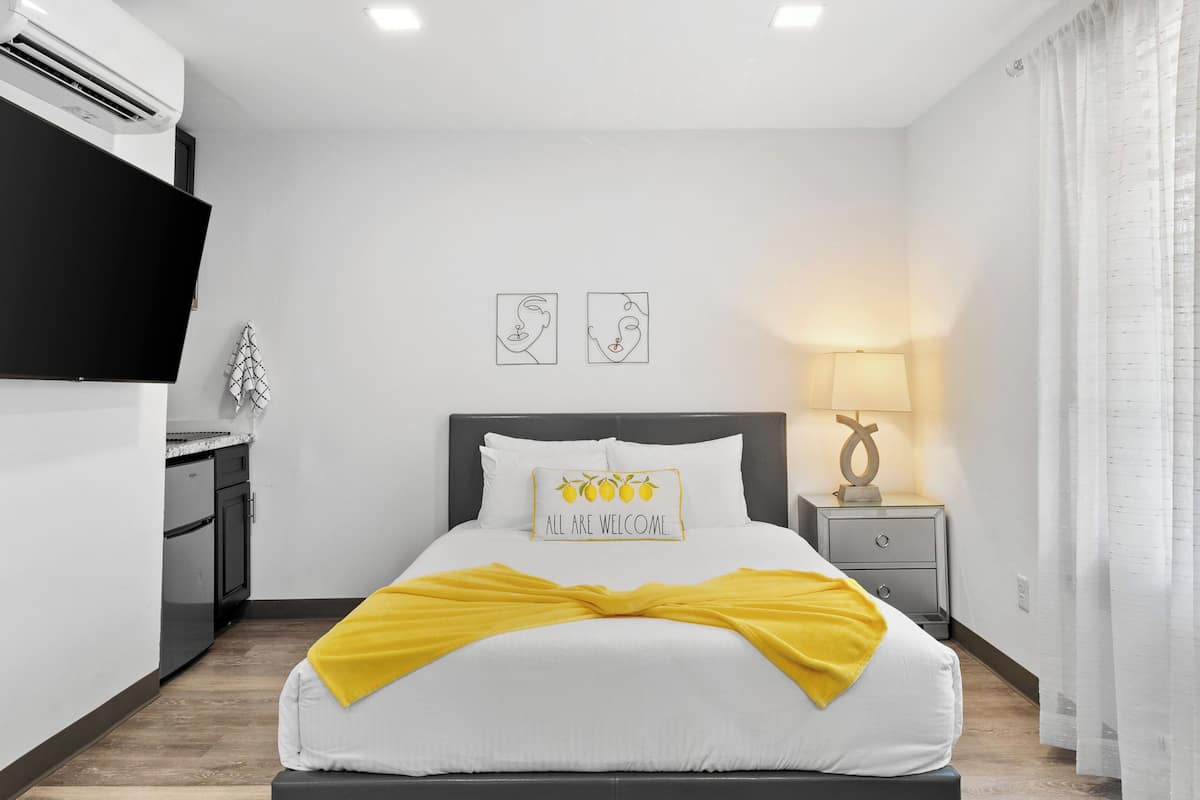 A hotel room with a bed, a nightstand, a lamp, and a flat-screen TV.