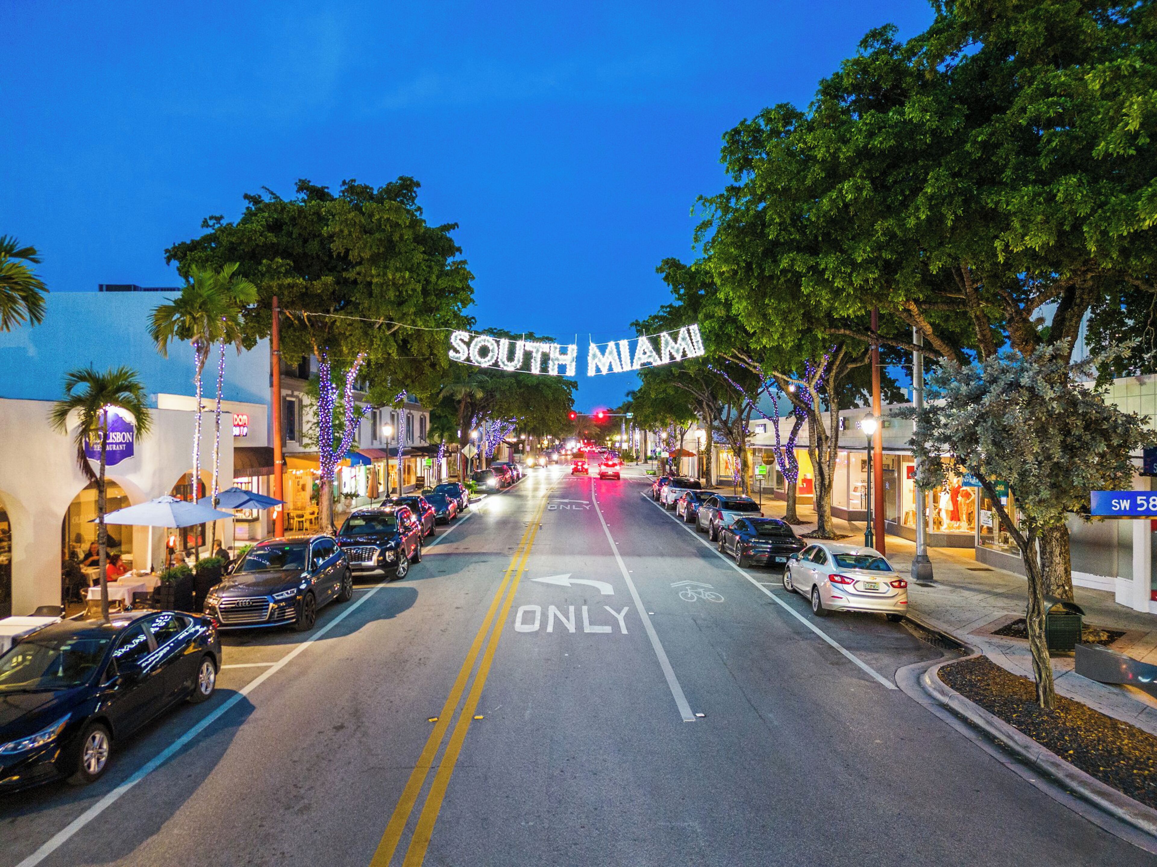 A street view with a 'SOUTH MIAMI' sign, cars parked on the side, and a bike lane.