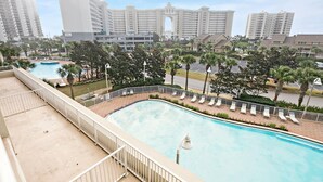 Un hotel con piscina, palmeras y rascacielos al fondo.