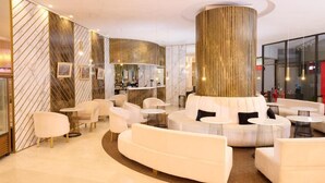 A modern lounge area with a central seating arrangement, a large cylindrical column, and a marble-patterned wall. - Grand Hotel Bucharest (Bucharest)