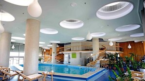 An indoor swimming pool with lounge chairs, a staircase, and a ceiling with circular light fixtures. - Grand Hotel Bucharest (Bucharest)