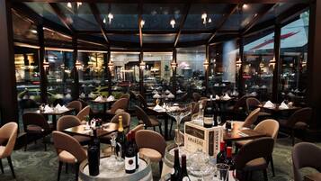 A restaurant with multiple tables, chairs, and wine bottles.