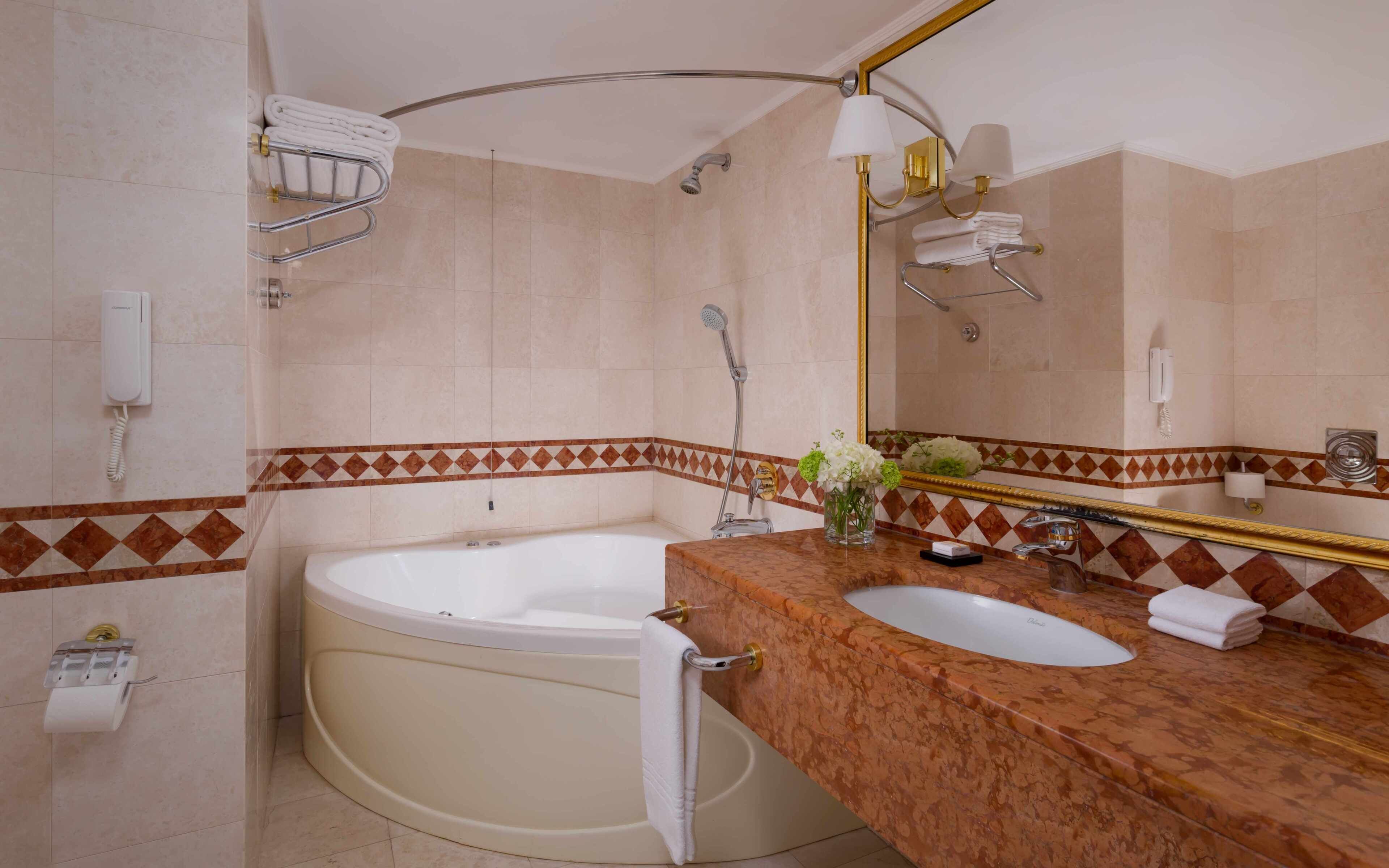 A bathroom with a bathtub, a sink, a mirror, and a towel rack.