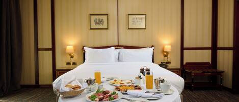 Habitación de hotel con una cama bien hecha, bufé de desayuno y dos cuadros en la pared.