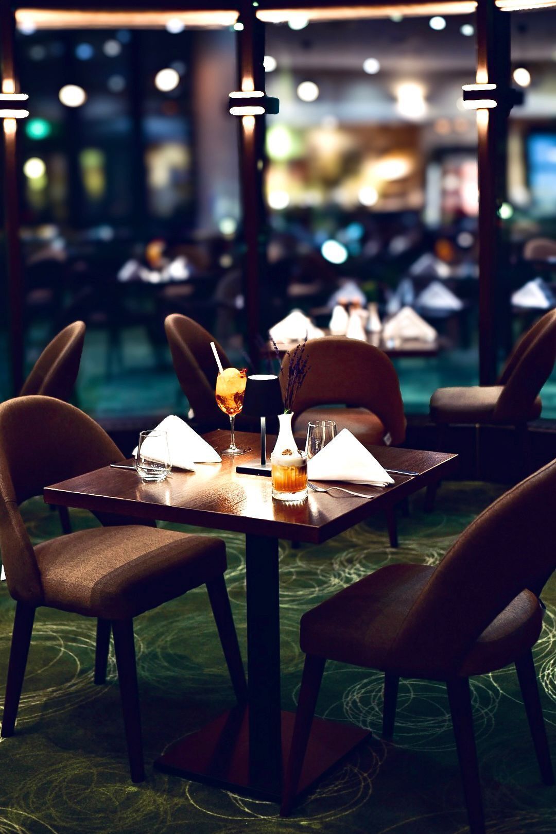 A restaurant with tables set for dining, featuring a bottle of beer and a glass of water.