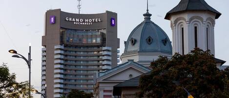 The Grand Hotel Bucharest building with a modern design, a dome structure, and a classical tower.