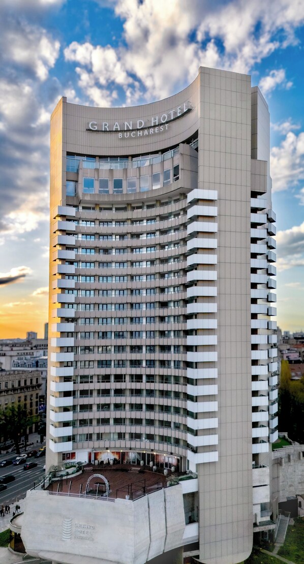 A high-rise hotel with a curved facade, multiple balconies, and a prominent entrance.