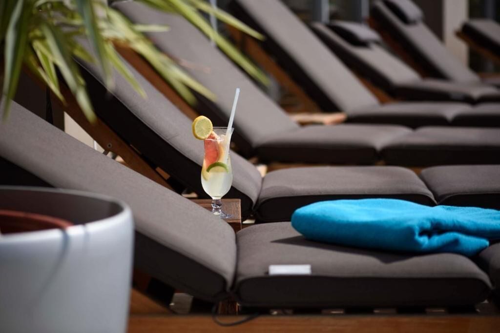 A row of sun loungers with a drink on one of them.