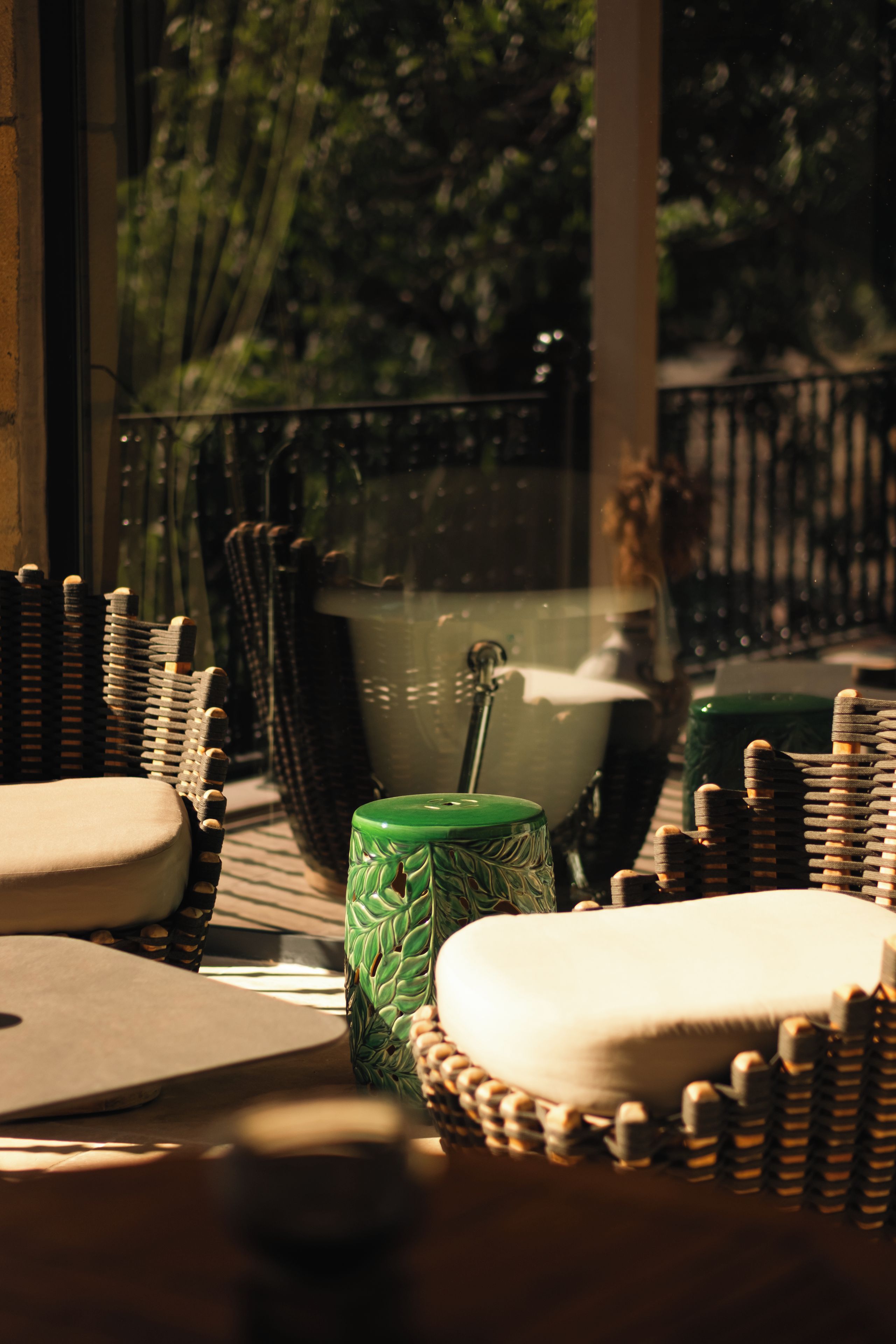 A wicker table with a green vase and a white cushion.