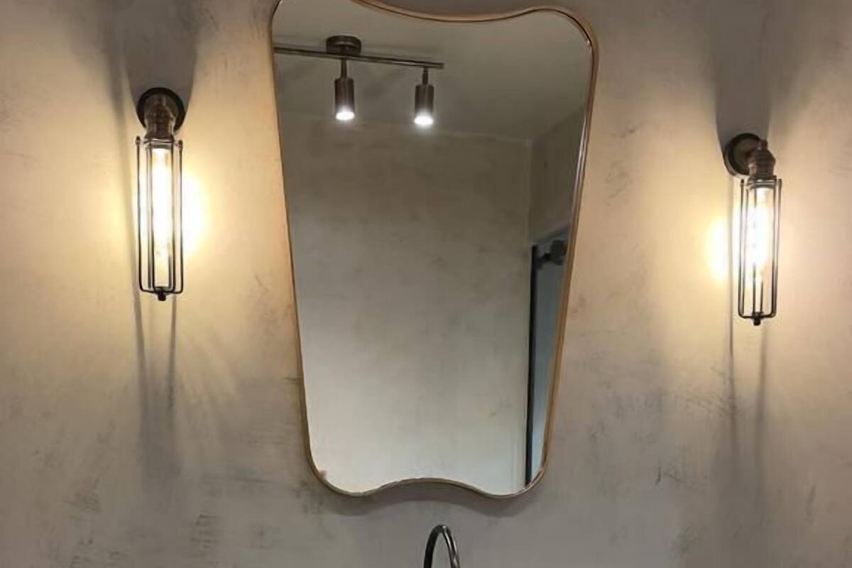 Un baño con un tocador moderno, un espejo grande e iluminación empotrada.