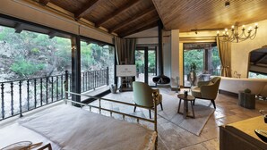 Un ampio balcone con vista sul verde, una zona relax con divano e poltrone, e una vasca da bagno spaziosa.