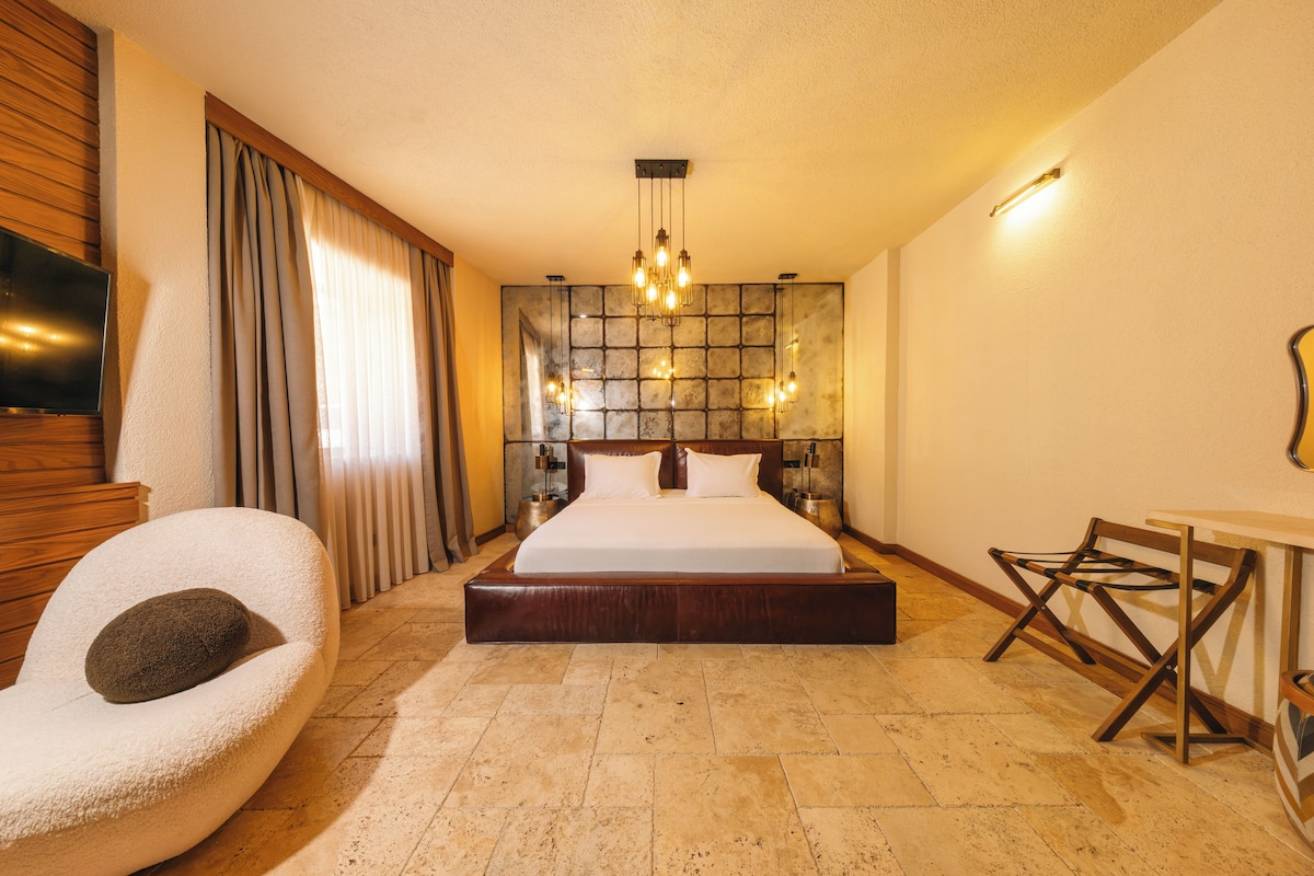 Ein Hotelzimmer mit einem großen Bett, einem Fernseher, einer Sitzecke und einer Steinwand.