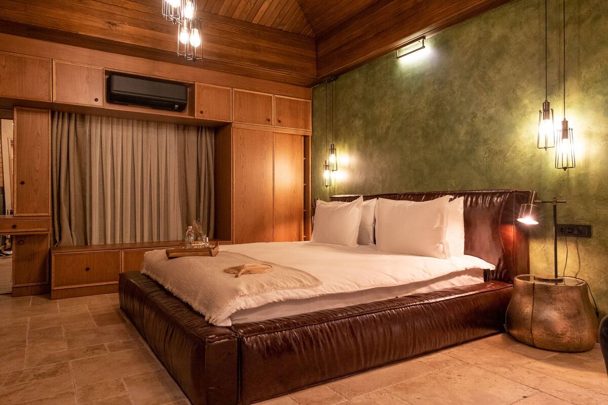 Un dormitorio con una cama grande, paneles de madera, un televisor de pantalla plana y una pared de acento verde.