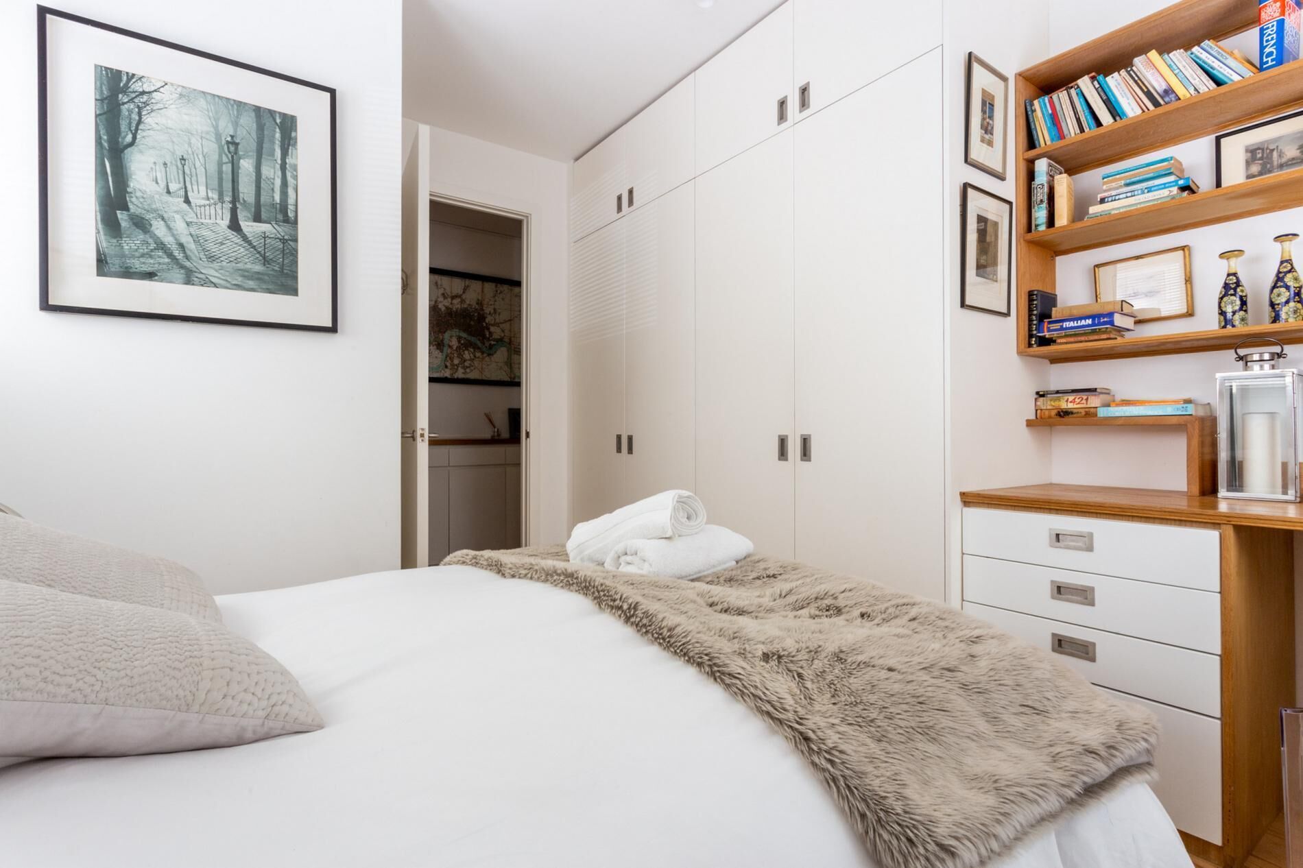 Un dormitorio con cama, armario, estantería y un cuadro en la pared.