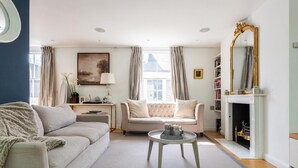 A living room with a sofa, a coffee table, a fireplace, and a bookshelf. - NEW Stunning 5BD Kensington House (London)