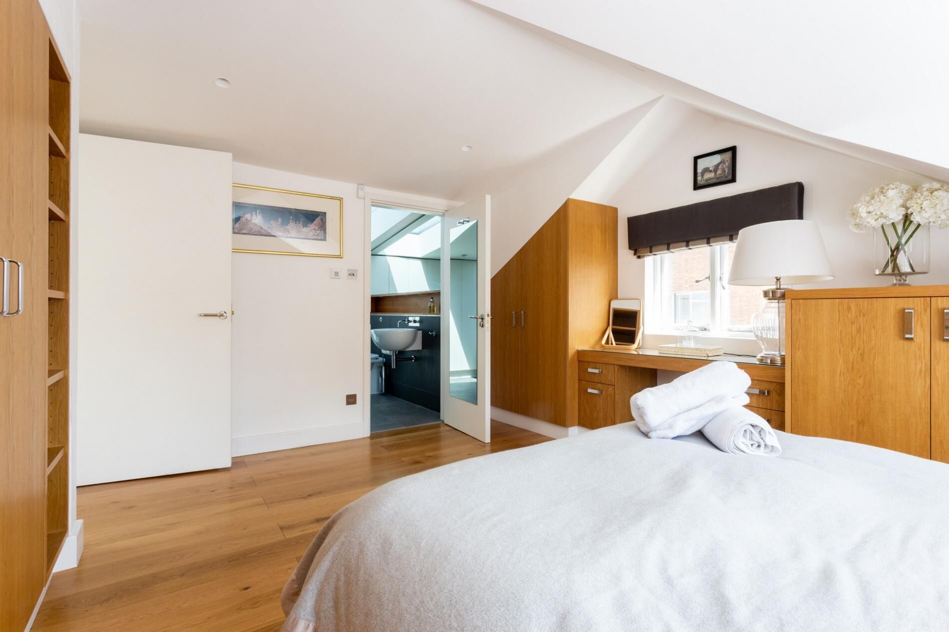 A bedroom with a bed, wooden wardrobe, and a bathroom visible through an open door.