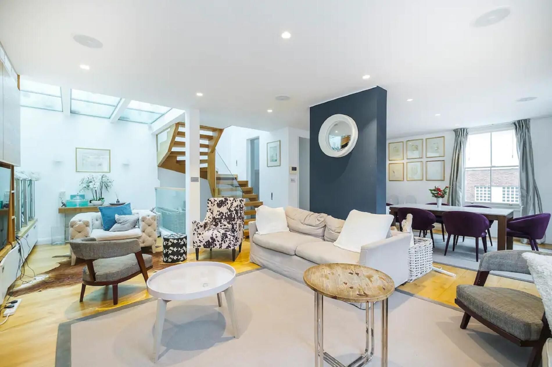 A spacious living room with a modern design, featuring a sofa set, a coffee table, and a dining area with a table and chairs.