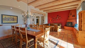 Un coin repas avec une table et des chaises en bois, un lustre et un mur d’accent de couleur rouge.