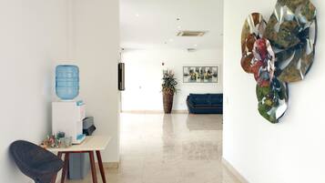 A modern living room with a blue water dispenser, a dark chair, a white table, and a blue sofa.