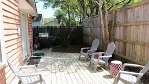 Una terraza de madera con asientos exteriores y una parrilla.