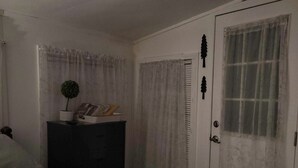 A bedroom with a bed, a dresser, a door with a window, and a small potted plant. - Relaxing 2 bedroom river side home. Home located in Banner Elk, NC  (Banner Elk)