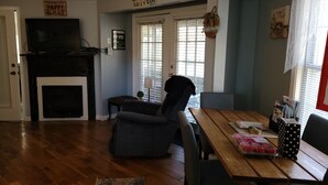 A cozy living room with a fireplace, a dining table with a vase of flowers, and a television on a stand. - Relaxing 2 bedroom river side home. Home located in Banner Elk, NC  (Banner Elk)