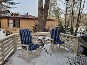 Eine Terrasse mit zwei gestreiften Stühlen und einem kleinen Tisch, umgeben von Schnee.