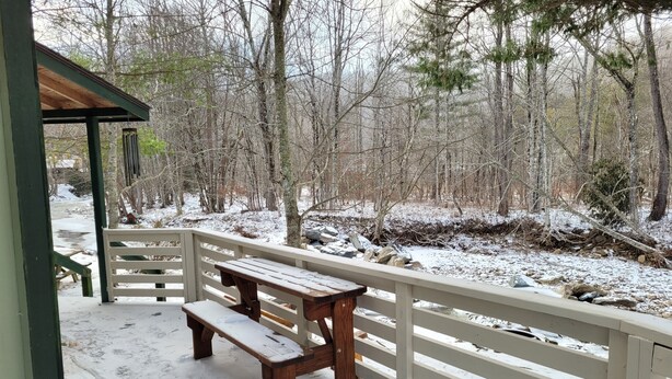A wooden deck with benches and a railing overlooking a snowy landscape with trees. - Relaxing 2 bedroom river side home. Home located in Banner Elk, NC  (Banner Elk)