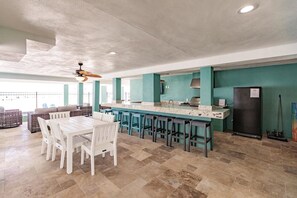 A spacious kitchen with a central island, bar stools, and a dining area with white chairs.