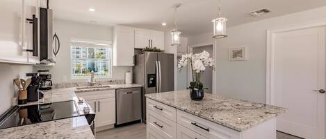 A modern kitchen with granite countertops, stainless steel appliances, and pendant lighting.