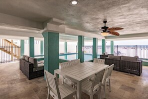 A spacious indoor area with a high ceiling, a white table with chairs, and a ceiling fan.