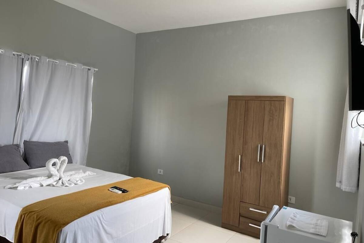 A hotel room with a bed, a wardrobe, and a bathroom area.