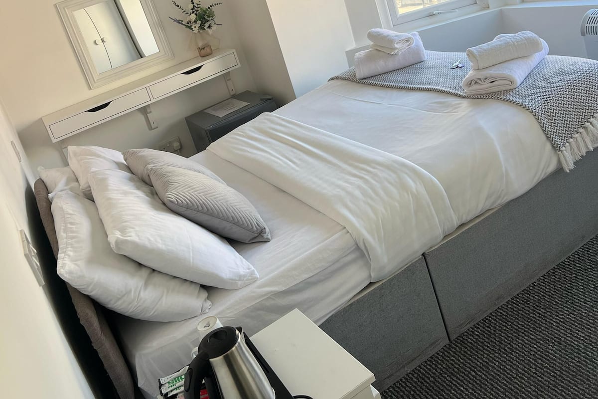A neatly arranged hotel room with a bed, bedside table, and a TV mounted on the wall.